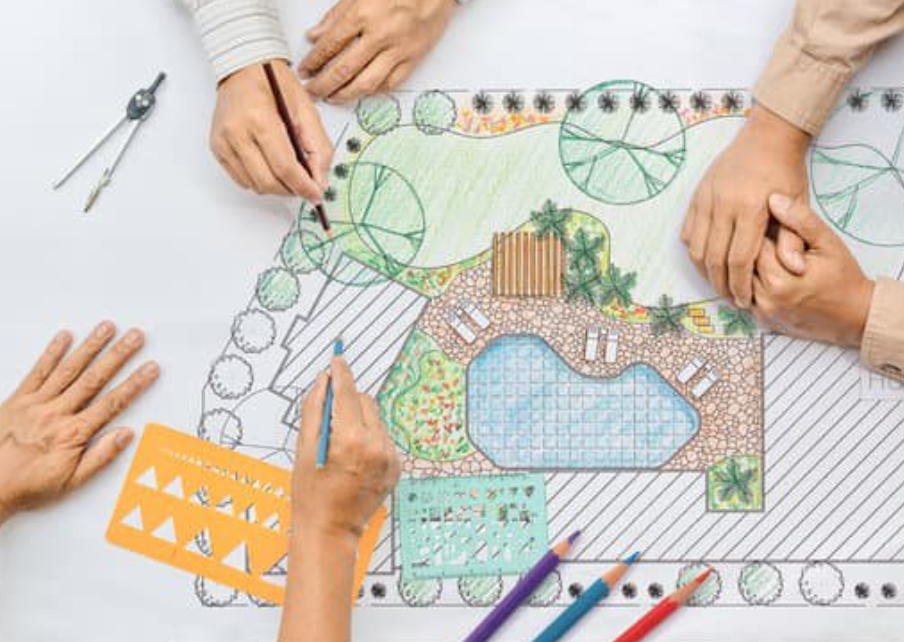 Hands sketching a colour landscape design plan featuring a swimming pool, trees, and decking.