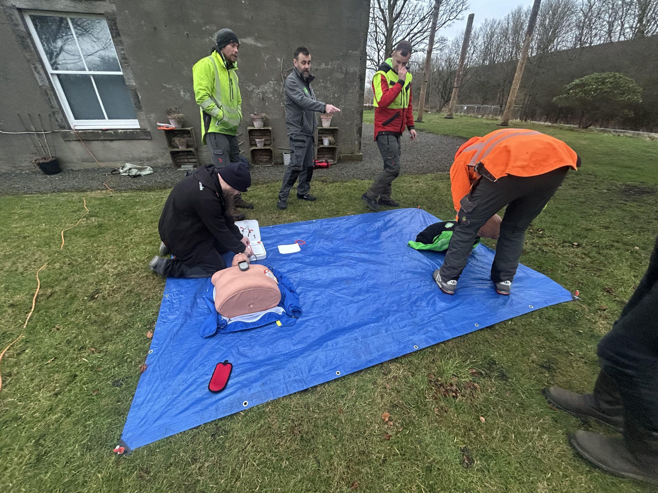 team practicing cpr on training mannequin outdoors
