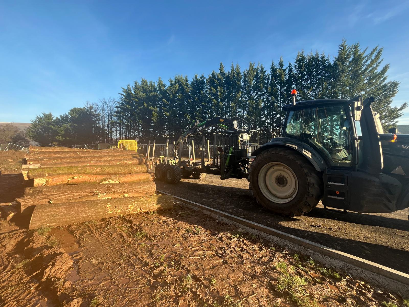tractor with forwarder trailer loading cut logs
