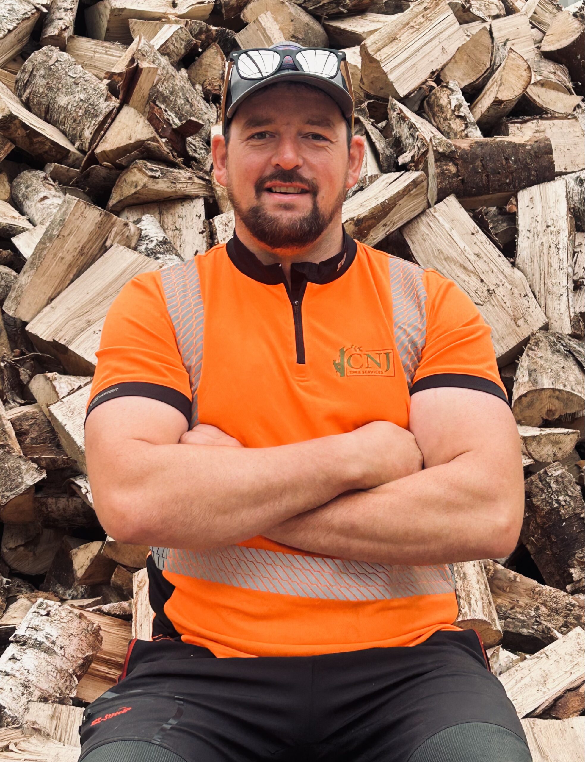 tree surgeon standing in front of firewood log pile